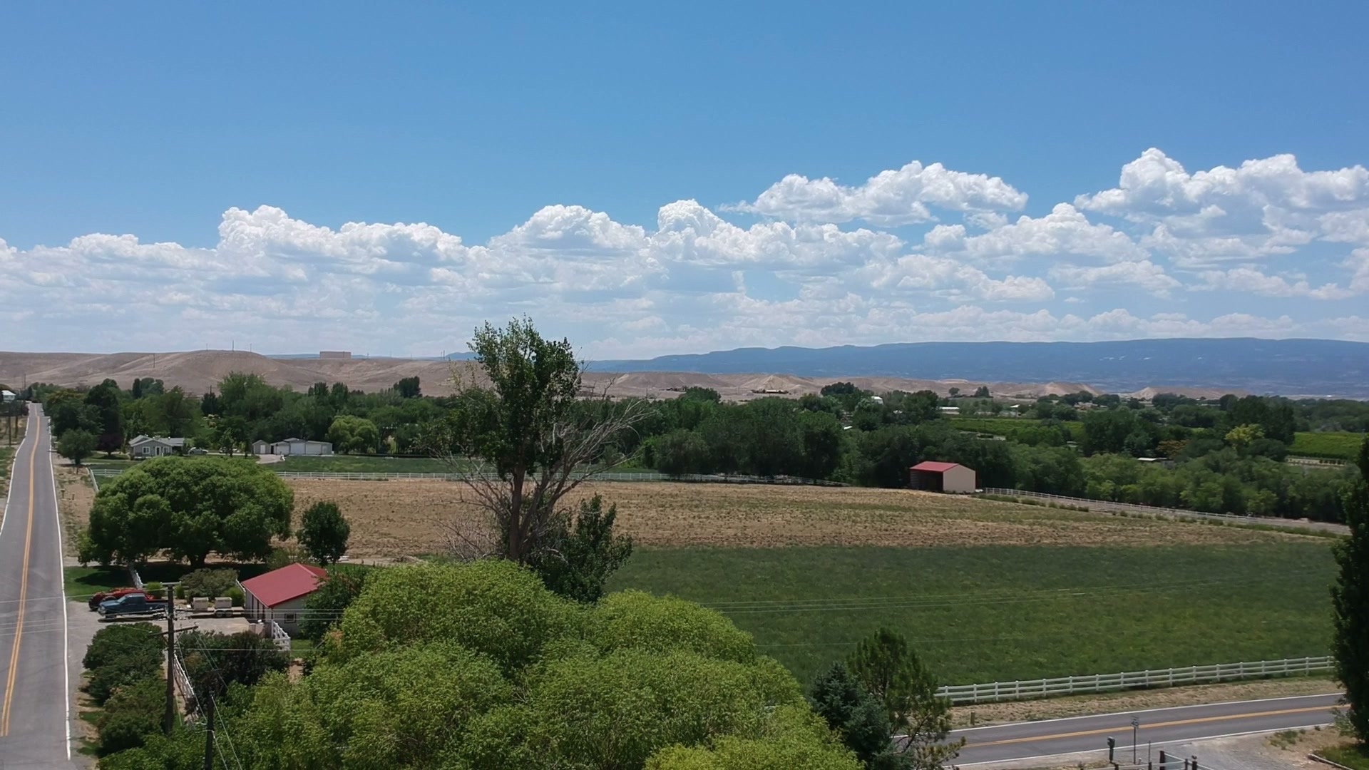 Two-lane road to the horizon across Colorado valley farmland, July 2017